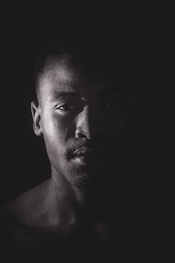 Artistic black and white portrait of a man with dramatic lighting and expressive gaze. HD phone wallpaper