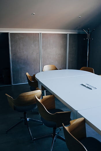 A minimalist, modern conference room featuring sleek wooden chairs and a spacious table. HD phone wallpaper