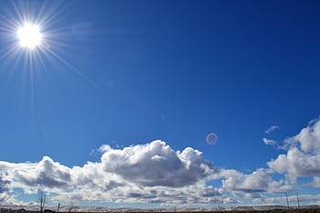 A vibrant capturing the sun shining over fluffy clouds in a blue sky. HD wallpaper