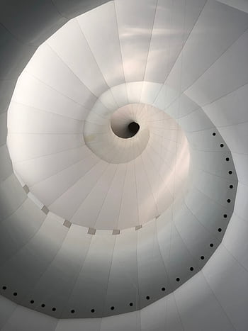Abstract view of a modern spiral staircase in neutral tones, showcasing geometric design and symmetry. HD phone wallpaper