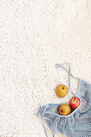 Apples in a blue mesh bag placed on a white carpet depicting freshness and simplicity. HD phone wallpaper