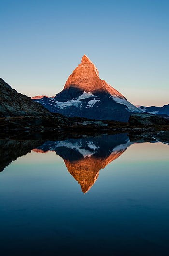 Captivating view of the Matterhorn reflected in a calm lake during sunset, showcasing nature's beauty. HD phone wallpaper