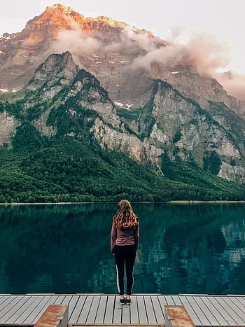 Woman standing at Klöntalersee in Switzerland with scenic mountain background. HD phone wallpaper