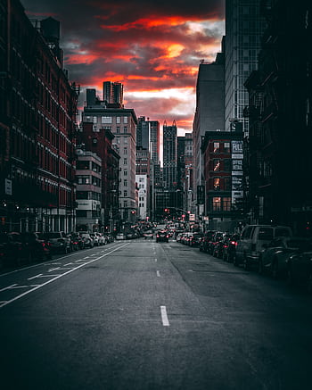 Moody city street with skyscrapers under a dramatic dusk sky. HD phone wallpaper