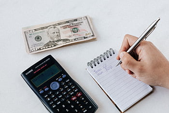 Close-up of budgeting items including calculator, cash, and notebook for financial planning. HD wallpaper