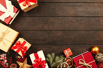 Red and white wrapped Christmas gifts and ornaments on wooden surface. HD wallpaper