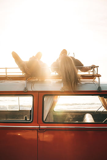 Two people enjoying a sunset on a vintage car's roof by the seaside, capturing a care summer vibe. HD phone wallpaper