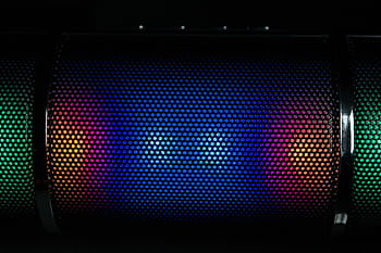 Vibrant LED lights illuminate a speaker grille with colorful patterns. HD wallpaper