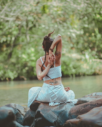 A woman in a yoga pose by a calm river, surrounded by nature, embodying peace and tranquility. HD phone wallpaper