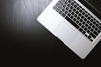 Top view of a sleek laptop on a dark wooden desk, showcasing modern technology. HD wallpaper