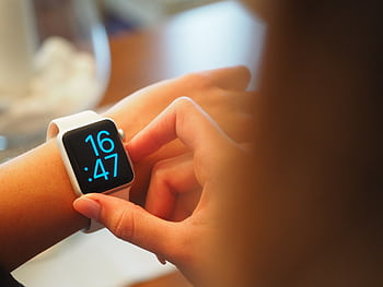 An individual operating a digital smartwatch displaying time with a blue interface. HD wallpaper
