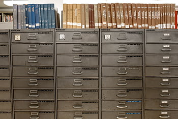 Organized filing cabinets stacked with indexed books in a library setting. HD wallpaper