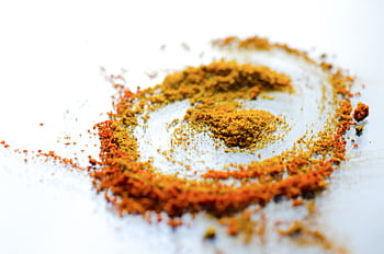 A vibrant array of colorful spices including turmeric and curry powder on a white background. HD wallpaper
