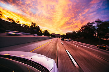 Motion blur of cars speeding on an Irvine highway at sunset with vibrant skies. HD wallpaper