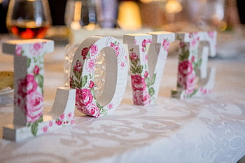 Floral 'LOVE' letters on a decorated dining table, perfect for weddings or romantic dinners. HD wallpaper