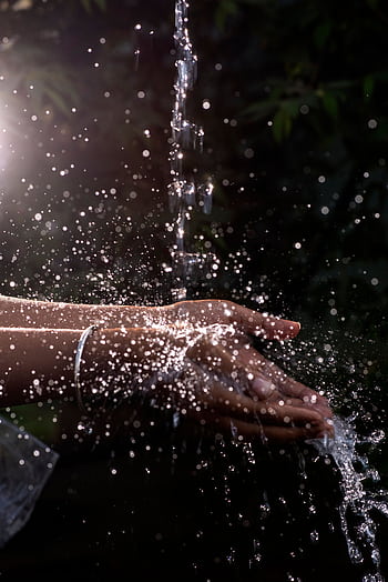 A vivid close-up of water splashing over cupped hands, capturing the essence of freshness and purity. HD phone wallpaper