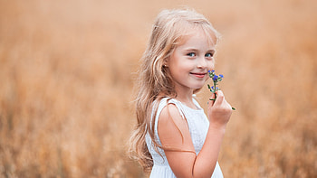 White Hair Smiling Cute Little Girl With Purple Flowers Is Wearing White Dress Standing In Blur Background Cute HD wallpaper
