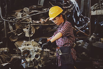 Woman engineer wearing safety gear, working on machine repair in an industrial setting. HD wallpaper