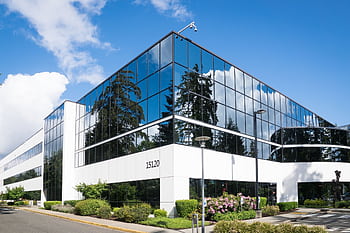 Contemporary office building in Redmond with reflective glass and lush greenery, captured on a sunny day. HD wallpaper