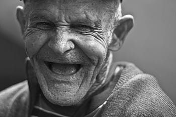 Close-up portrait of an elderly man laughing, capturing a joyful and emotive expression. HD wallpaper