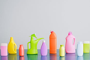 A vibrant assortment of cleaning product containers arranged on a reflective surface, perfect for household sanitation themes. HD wallpaper