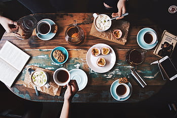 Overhead view of a cozy coffee table setup with cups, snacks, and books, perfect for a relaxing afternoon. HD wallpaper