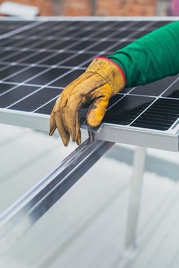 Close-up of a worker's hand in protective glove installing a solar panel. HD phone wallpaper