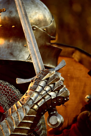 Detailed view of a medieval knight's steel gauntlet grasping a sword, highlighting historical armor. HD phone wallpaper