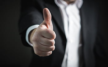 A close-up of a man's thumbs up gesture, symbolizing success and agreement. HD wallpaper