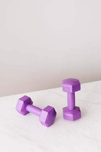 Pair of vibrant purple dumbbells on a marble surface, ideal for fitness themes. HD phone wallpaper