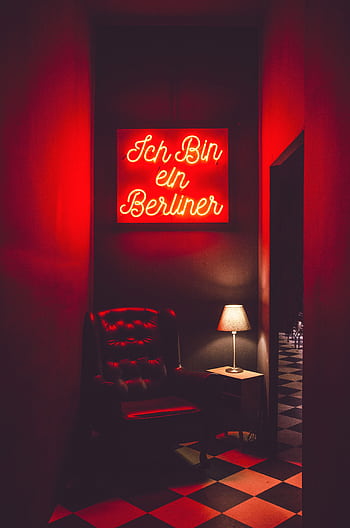Stylish dimly lit interior featuring a neon sign above a leather armchair and table lamp. HD phone wallpaper