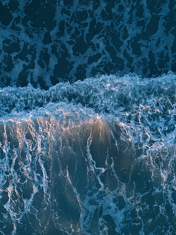 Breathtaking aerial view of crashing ocean waves at sunset, showcasing nature's beauty. HD phone wallpaper