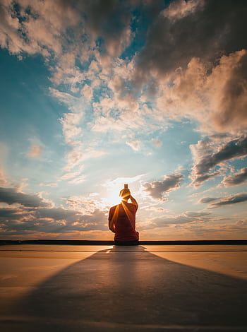 Silhouette of a figure meditating against a stunning sunset sky, creating a serene and peaceful atmosphere. HD phone wallpaper