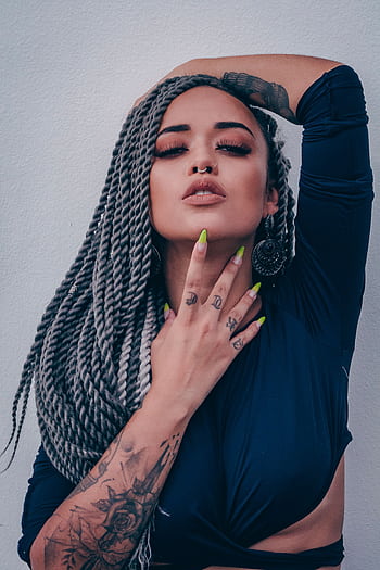 Close-up portrait of a fashionable woman with braided hair, tattoos, and a confident pose. HD phone wallpaper