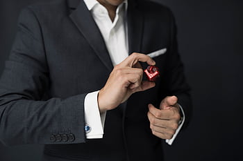 A businessman elegantly dressed in a suit holding a fidget cube, symbolizing stress management. HD wallpaper