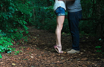 A loving couple embracing on a secluded forest pathway surrounded by lush greenery. HD wallpaper