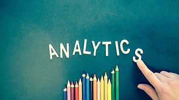 Colored pencils and letters spelling 'ANALYTICS' on a textured background with a hand. HD wallpaper