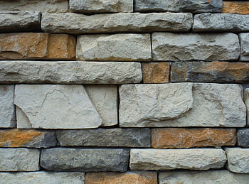 Close-up of a textured stone wall with a variety of natural colors. HD wallpaper