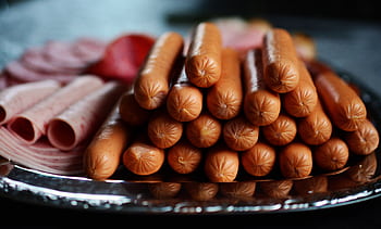 Delicious assortment of hot dogs and sliced meats artfully arranged on a silver platter. HD wallpaper