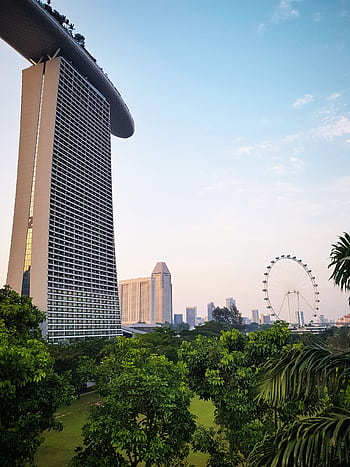 View of Marina Bay Sands against Singapore skyline with lush greenery in the foreground. HD phone wallpaper