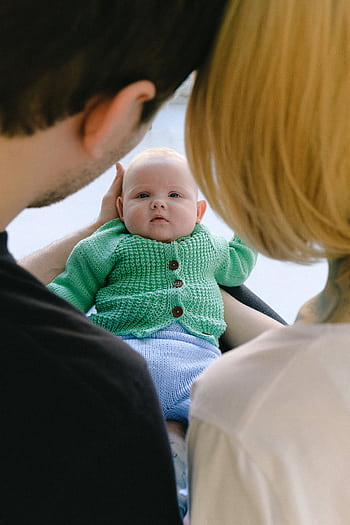 A family warmly gazing at their smiling baby indoors, symbolizing love and togetherness. HD phone wallpaper