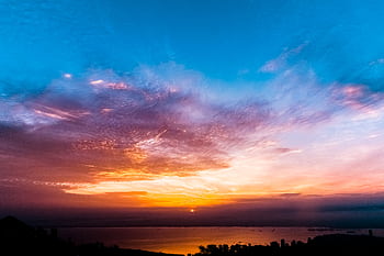 Captivating sunset sky with vibrant colors over a calm ocean horizon. HD wallpaper