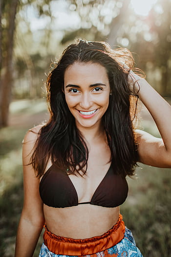 Care woman in bikini enjoying sunny day outdoors with a vibrant smile. HD phone wallpaper