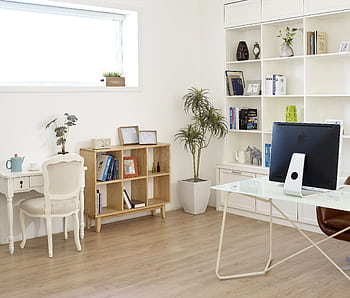 Contemporary home office setup with natural light, featuring modern decor, desk, computer, and bookshelves. HD wallpaper