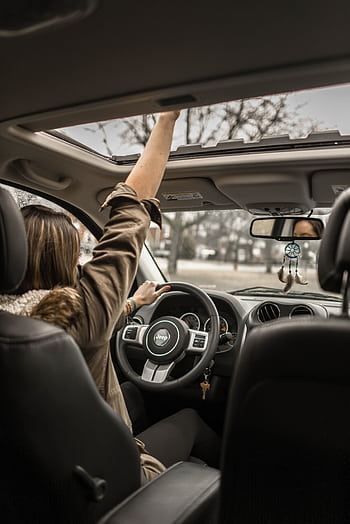 A young woman enjoying a drive with the sunroof open, showing car interior detail. HD phone wallpaper