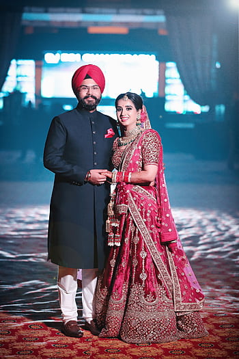 A joyful Indian couple in traditional wedding attire, celebrating their special day indoors. HD phone wallpaper