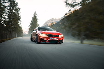 High-speed red sports car driving through scenic mountain road with blurred background HD wallpaper
