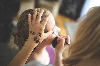 Close-up of a makeup artist applying cosmetics to a woman's face indoors. HD wallpaper