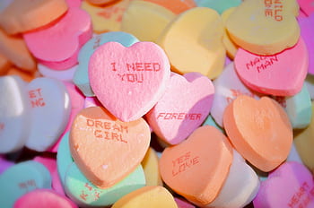 A pile of colorful heart-shaped candies with romantic messages, ideal for Valentine's Day. HD wallpaper