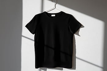 Minimalist of a black t-shirt on a hanger with dramatic shadows on a white wall. HD wallpaper